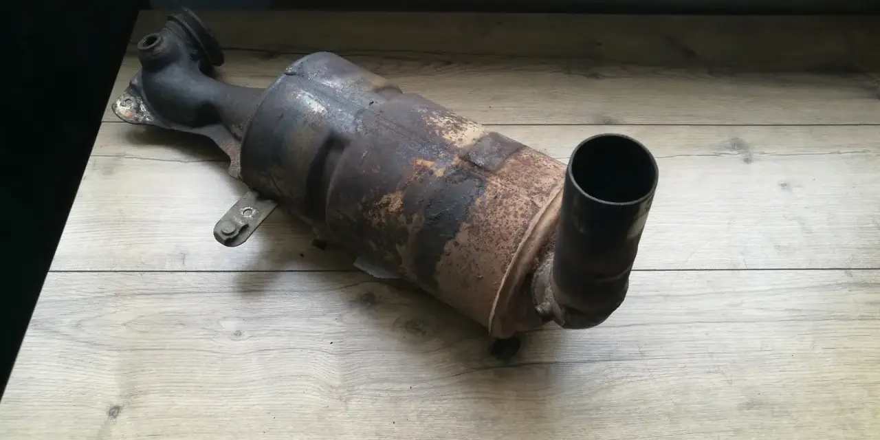 Zardzewiały, zużyty filtr DPF na drewnianym blacie.