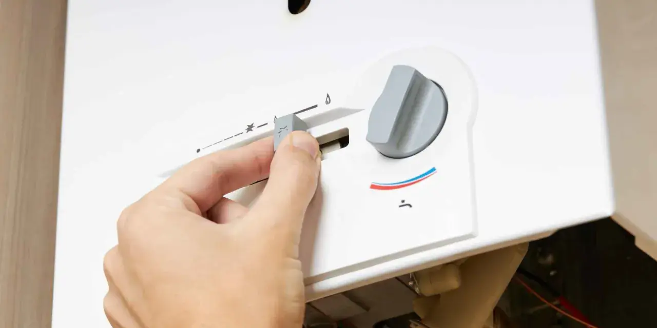 Mano regola la manopola di uno scaldabagno a gas Bosch, forse per risolvere problemi di funzionamento.