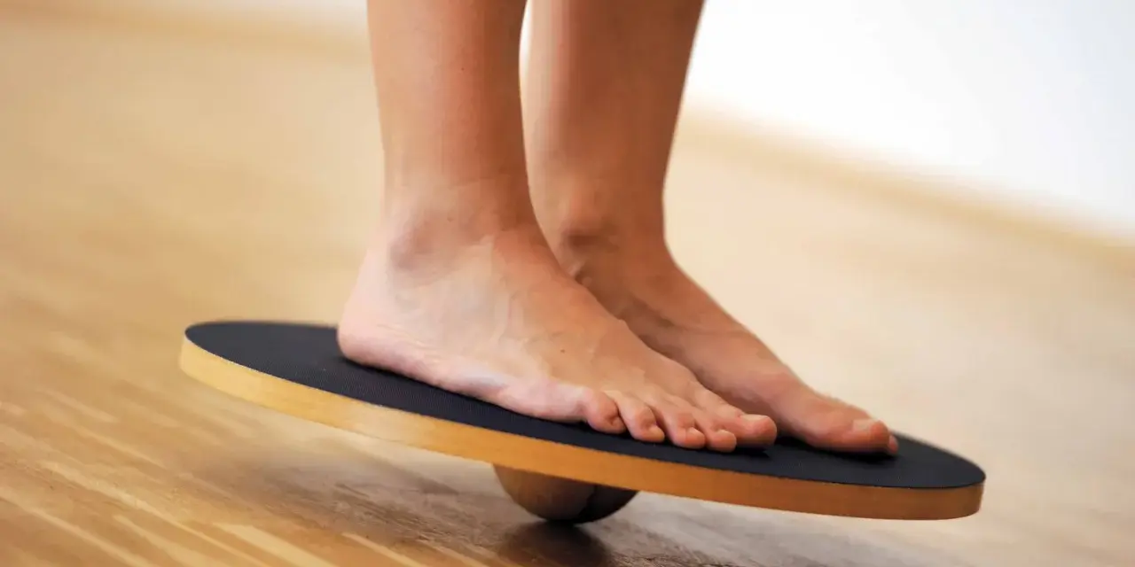 Piedi su una tavola di equilibrio, utili per esercizi di riabilitazione per distorsione caviglia.