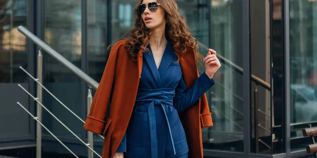 Quelle veste avec robe bleu marine pour mariage ? Un manteau rouille chic complète cette tenue élégante.