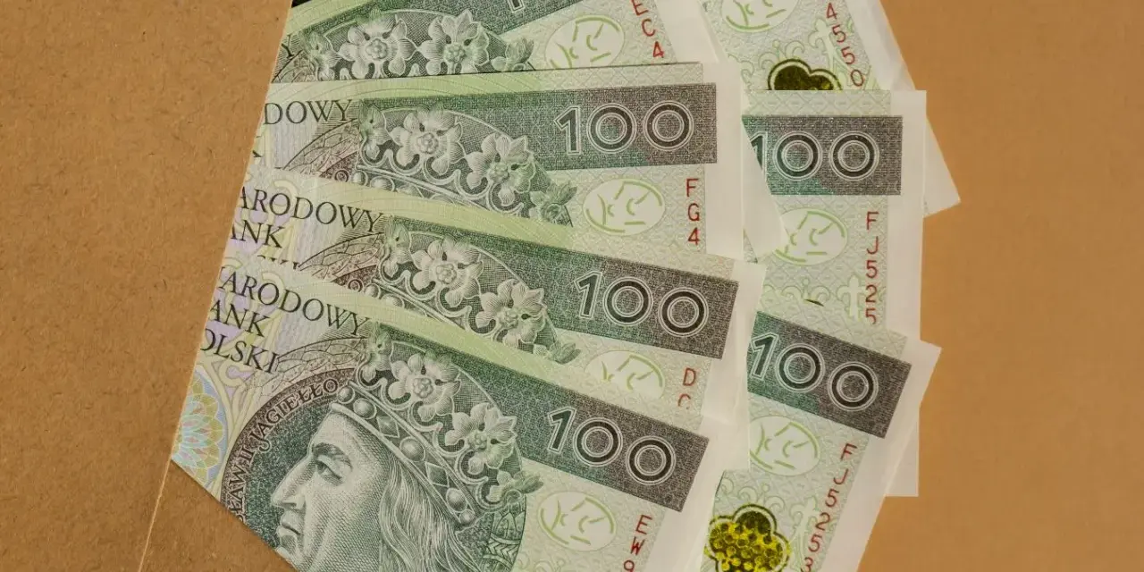 Stos banknotów 100 zł, idealnych na prezent, ile daje się na komunię?