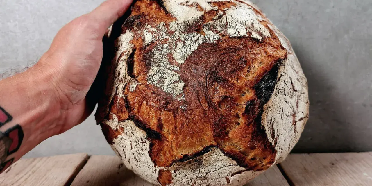 Eine Hand hält ein knuspriges Brot. Perfekt zum Bier!