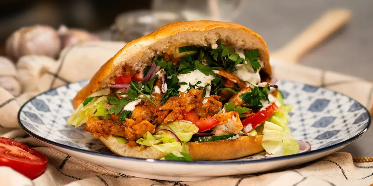 Domowy kebab z kurczakiem, warzywami i sosem na talerzu.