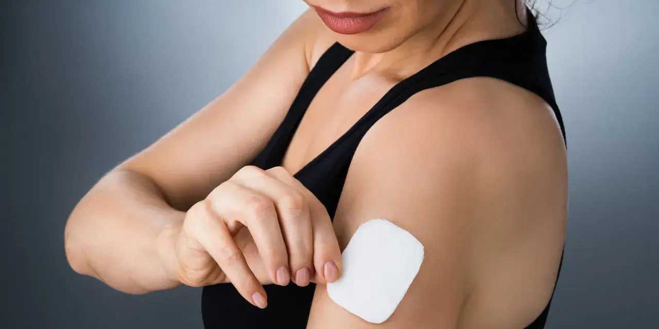 Kobieta przykleja plaster antykoncepcyjny na ramię. Dyskretny sposób na kontrolę płodności.