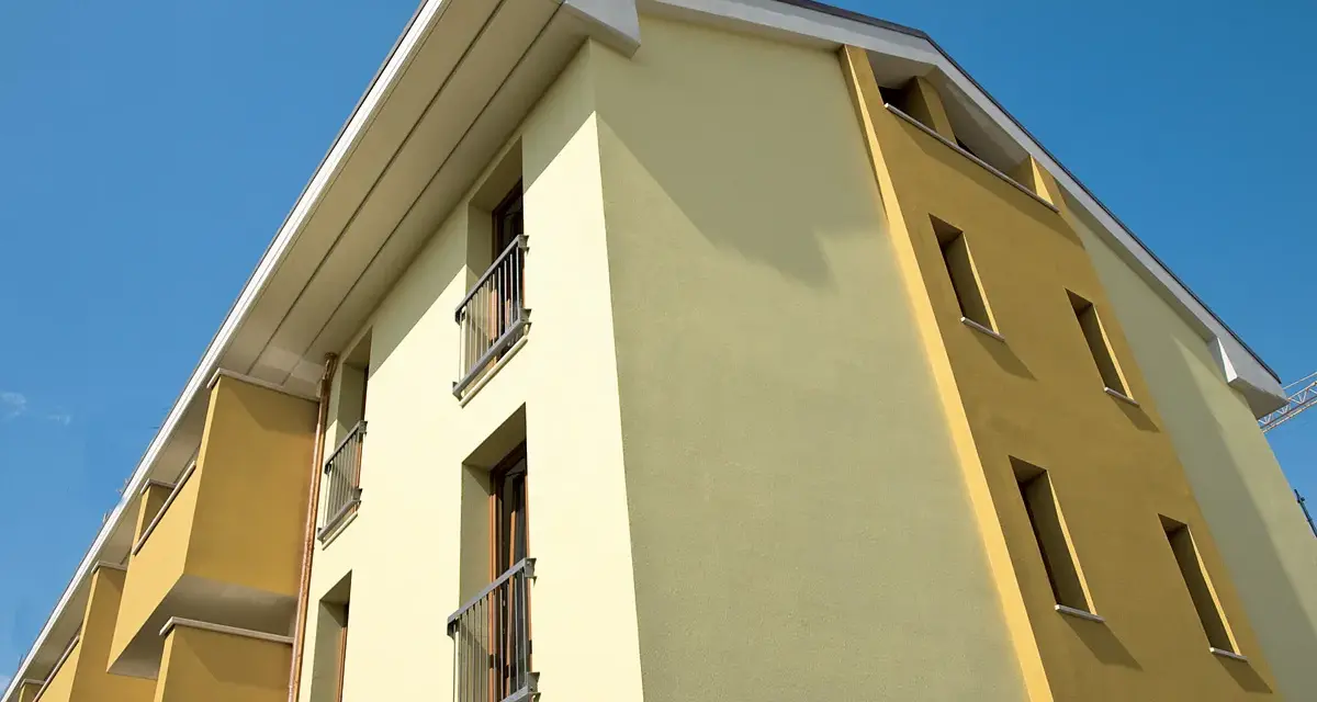 Edificio moderno con facciata bicolore, protetta da vernice isolante termica Mapei, sotto un cielo azzurro.