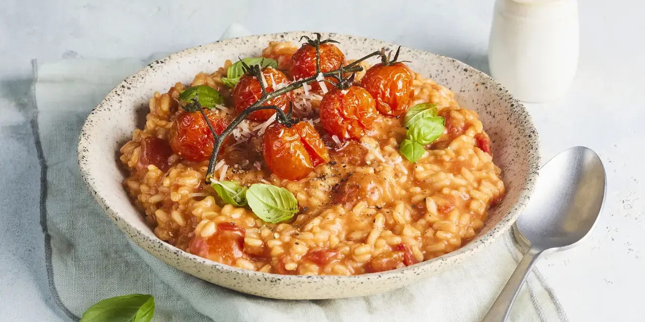 Cremiges Tomaten Risotto, garniert mit frischen Basilikumblättern und gerösteten Kirschtomaten. Ein Genuss für jeden Liebhaber italienischer Küche.