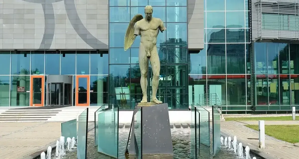 Igor Mitoraj dzieła: anielski tors na tle nowoczesnego budynku z fontanną.