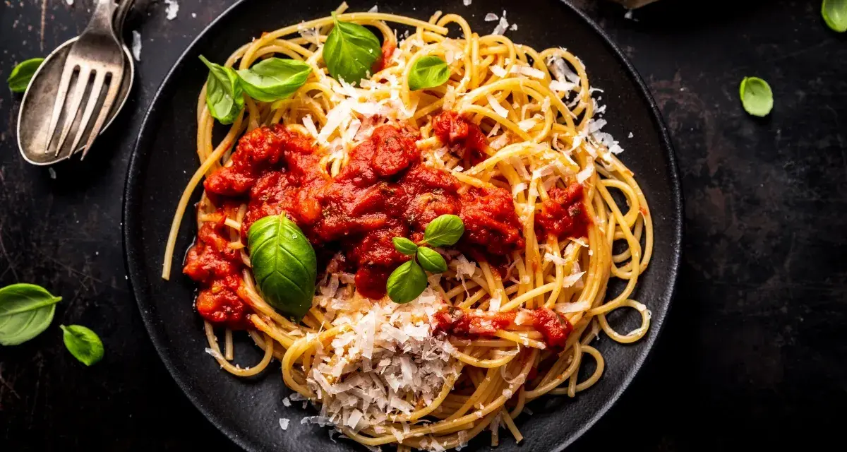 Talerz spaghetti z sosem pomidorowym, parmezanem i bazylią.