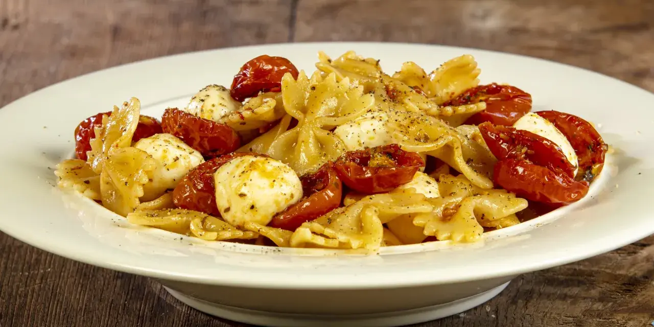 Farfalle con pomodorini confit, mozzarelline e un tocco di acciughe. Un piatto semplice e gustoso.