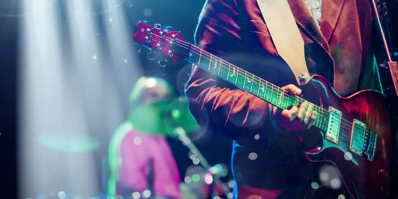 Koncertowe emocje! Gitarzysta gra na scenie, a w tle widać perkusistę. To jakby występ znanych zespołów muzycznych zagranicznych.