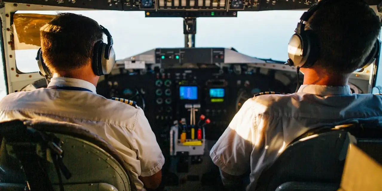Dwóch pilotów samolotu w słuchawkach na tle kokpitu.