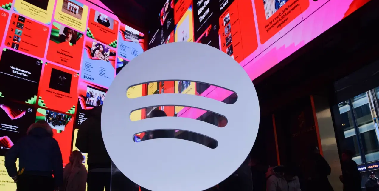 Duże logo Spotify na tle ekranów z podsumowaniami słuchania, w tym informacją o najpopularniejszym artyście na Spotify.
