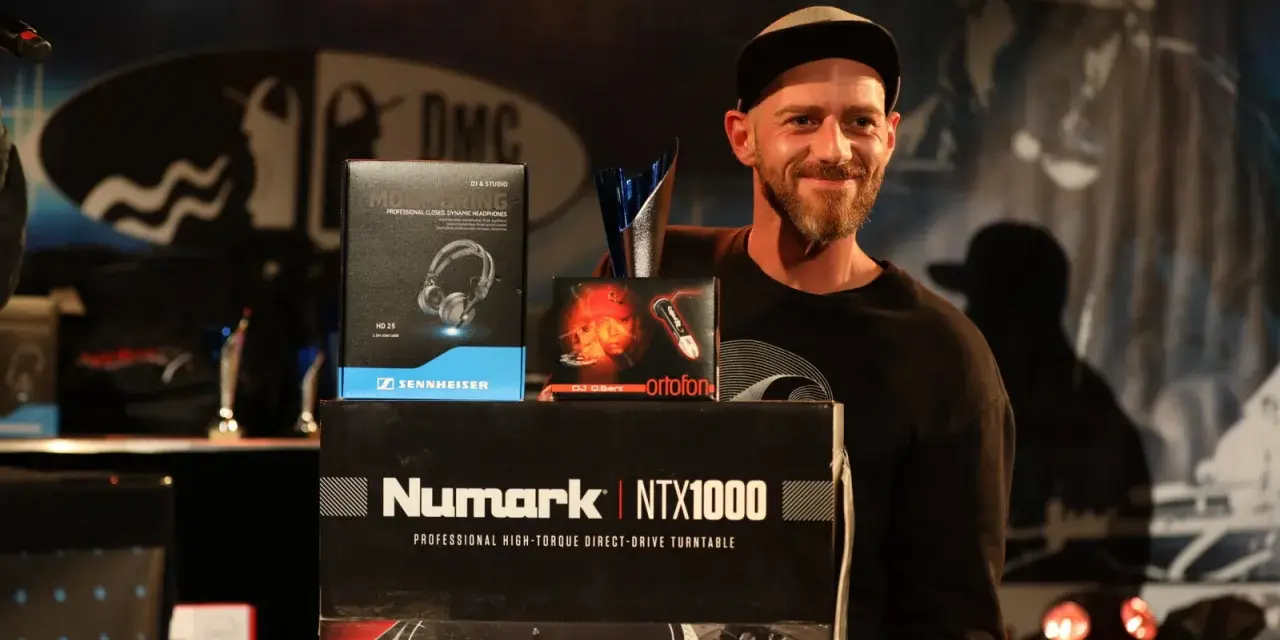Un DJ souriant pose avec des prix et du matériel, dont des casques Sennheiser et un tourne-disque Numark. Une liste DJ internationale est visible.