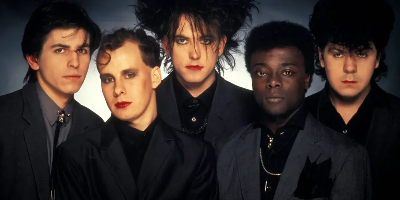 The Cure w pełnym składzie, z charakterystycznym makijażem i fryzurami, prezentują swoje kultowe utwory.