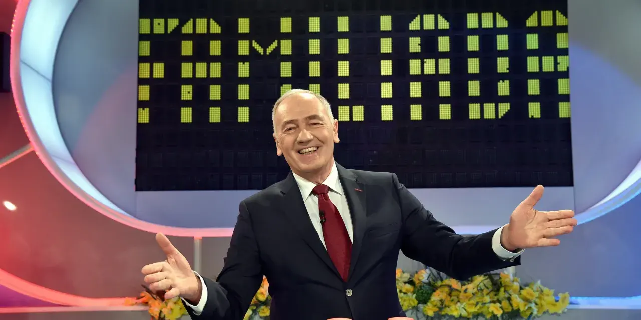 Uśmiechnięty prowadzący w garniturze na tle planszy z zielonymi polami, jak w Familiadzie. Ile lat ma ten program?