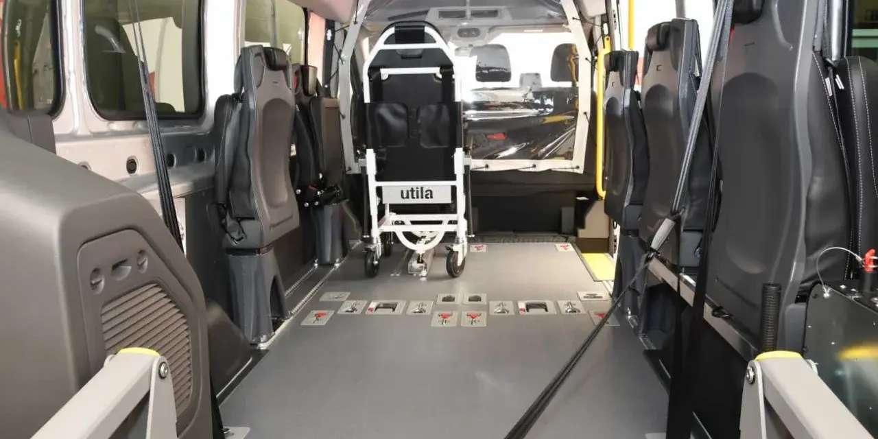 Innenraum eines Rollstuhlfahrzeugs, das als Taxi-Ersatz dient. Sitze und Rollstuhlhalterungen sind sichtbar.