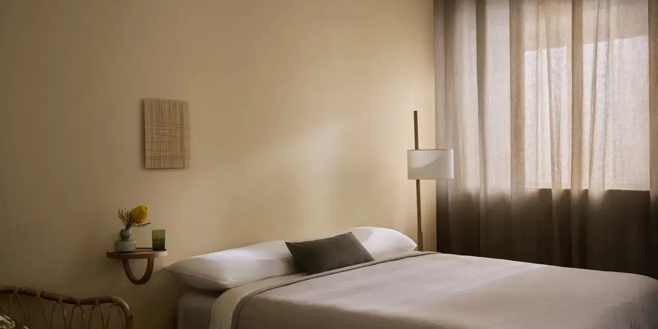 Ett lugnt sovrum med beige väggar, en bekväm säng och en golvlampa. Perfekt för att måla sovrum i en avkopplande stil.