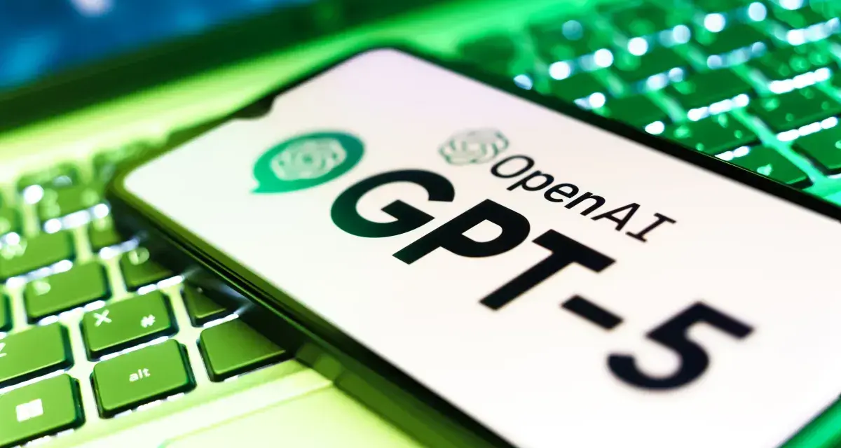 Ekran smartfona z logo OpenAI i napisem GPT-5 leży na podświetlanej zielonej klawiaturze.