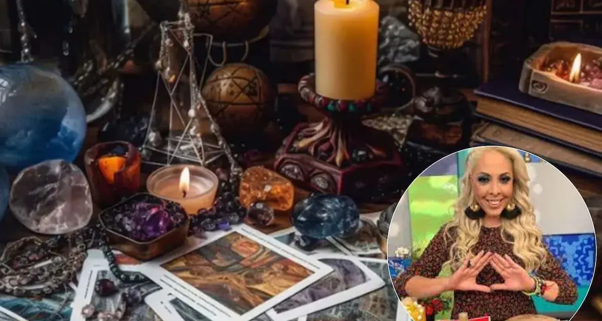 Mesa esotérica con cartas, cristales y velas. Una mujer sonríe haciendo un gesto con las manos, quizás buscando cómo atraer el amor.
