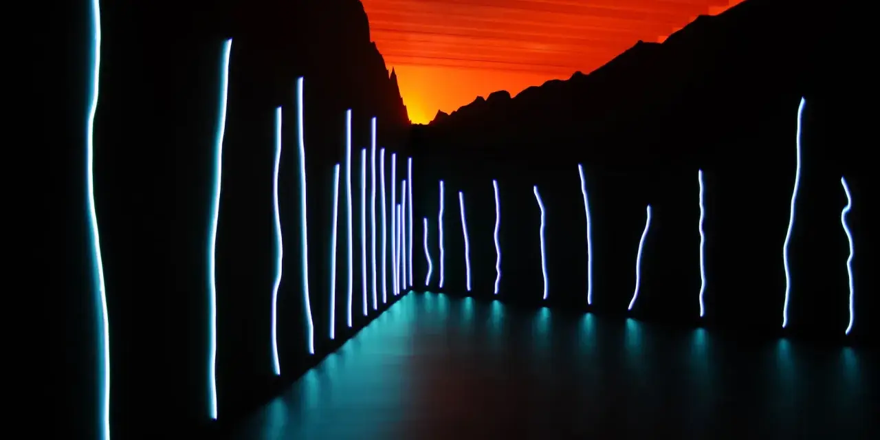 Installation lumineuse de Claude Lévêque, avec des néons bleus sur fond de ciel orangé et de montagnes sombres.