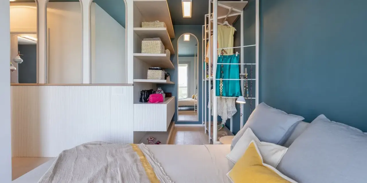 Progetto camera da letto con cabina armadio: letto, scaffali con cesti, abiti appesi e specchi ad arco.