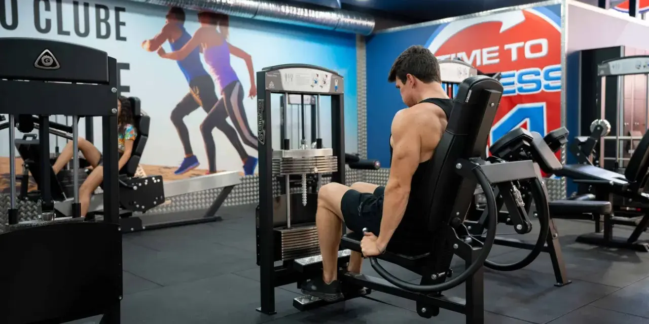 Man tränar ben på en **floor press**-maskin i ett modernt gym.