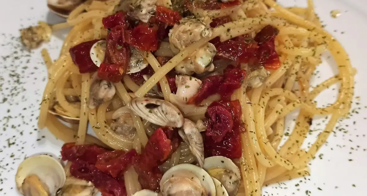 Spaghetti con lupini e pomodorini secchi, un piatto di mare saporito e profumato, guarnito con prezzemolo tritato.