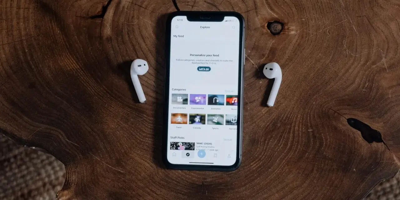 iPhone z AirPods na drewnianym tle.