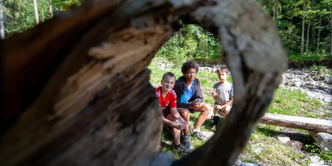 Trois enfants profitent d'une pause en forêt, rappelant l'importance du respect des locaux et de la nature.