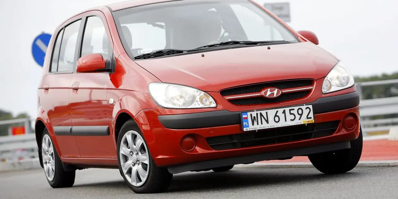 Czerwony Hyundai Getz na drodze. Kierowca za kierownicą, widoczna tablica rejestracyjna WN 61592.