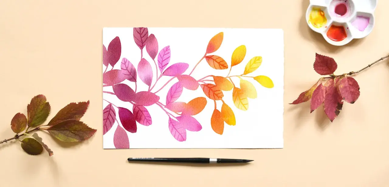 Aquarelle feuilles aux teintes roses, oranges et jaunes, évoquant l'automne. Une palette de couleurs et un pinceau sont disposés à côté.