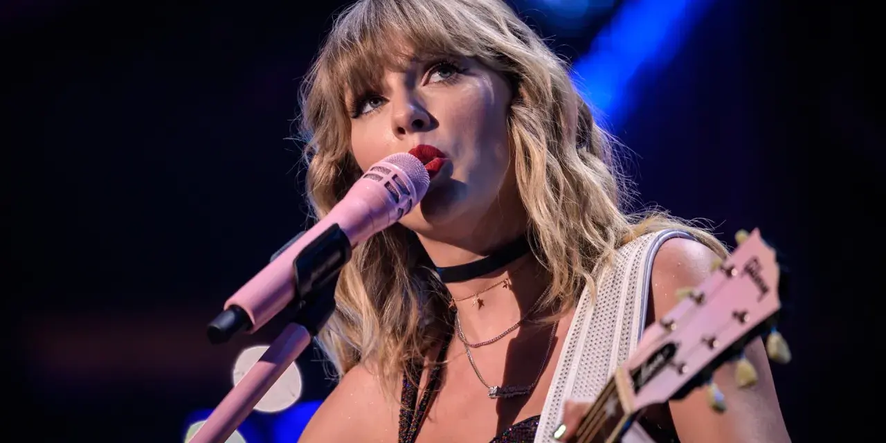 Taylor Swift śpiewa do różowego mikrofonu, grając na gitarze. To scena z jej epickiej trasy "reputation stadium tour", która na zawsze zmieniła jej wizerunek.