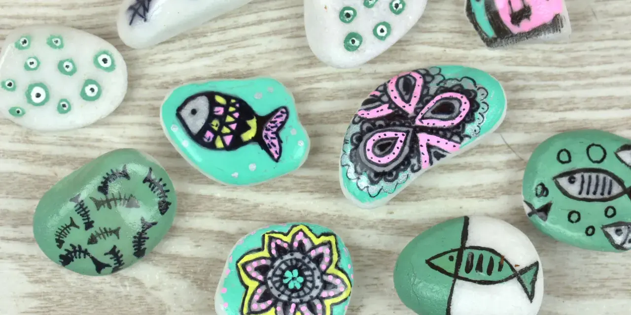 Ideas para pintar piedras de playa: peces, flores y diseños abstractos en tonos turquesa, blanco y rosa.
