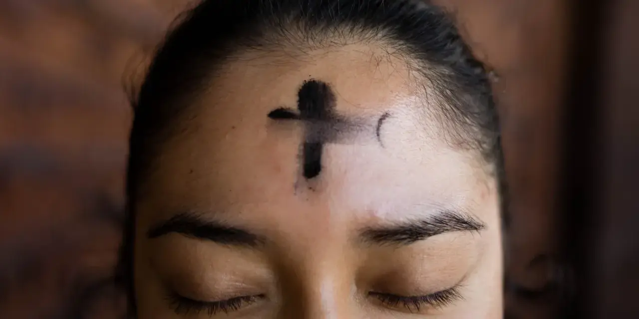 A cross of ashes marks a forehead, a solemn reminder of scripture for Ash Wednesday.