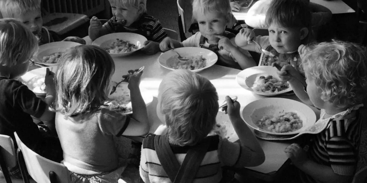 Kinder essen gemeinsam Brei. Ein Junge isst genüsslich, ein anderes Kind schaut nachdenklich. Erinnerungen an Kindheits Eis.