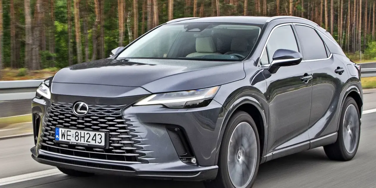 Szary Lexus RX 2026 jedzie po drodze, las w tle.