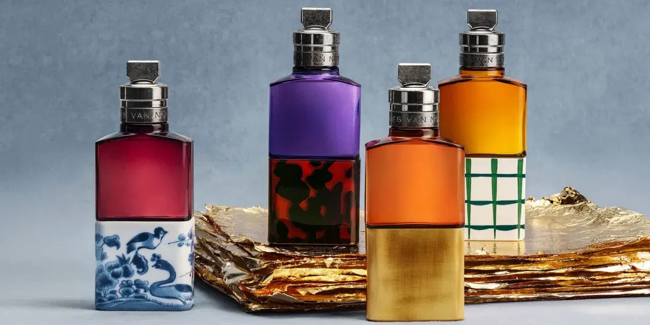 Vier bunte Parfumflaschen mit silbernen Verschlüssen auf goldenem Untergrund.