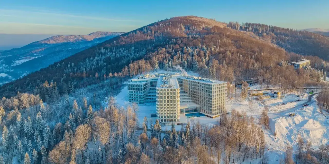 Nowoczesny hotel Crystal w zimowej scenerii, otoczony ośnieżonym lasem. To idealne miejsce na wypoczynek w Wiśle, górskim kurorcie.
