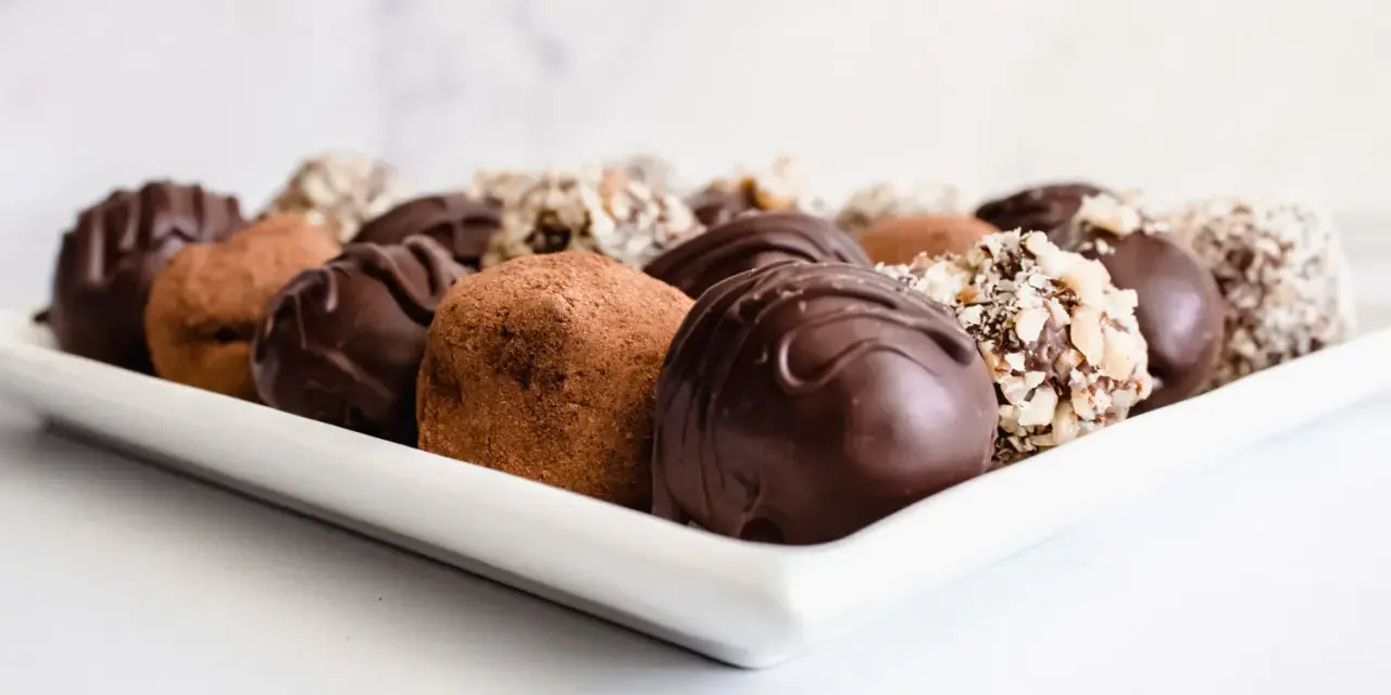 Variedad de trufas de chocolate, algunas cubiertas de cacao y otras con frutos secos picados. ¡Perfectas para aprender como hacer trufas de chocolate!