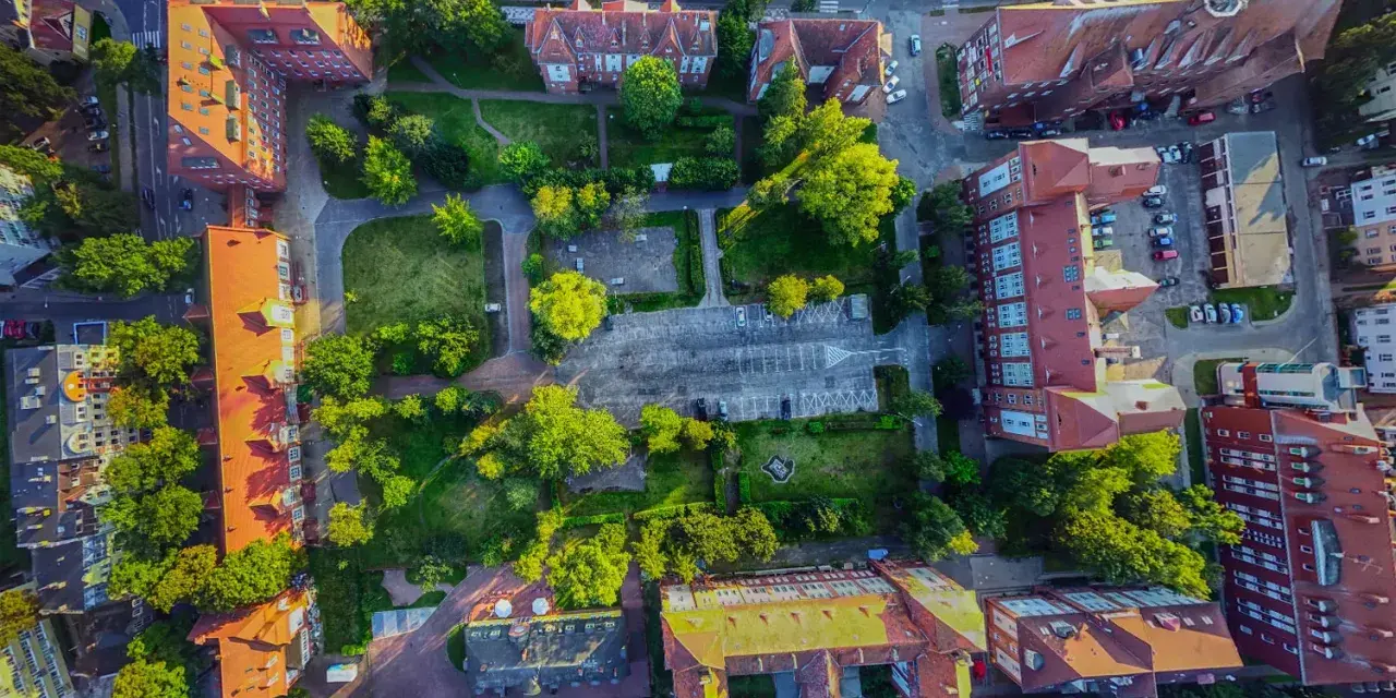 Widok z lotu ptaka na zabudowania i zieleń w Świnoujściu. Spacer po promenadzie i odkrywanie jej atrakcji z tej perspektywy to niezapomniane wrażenia.