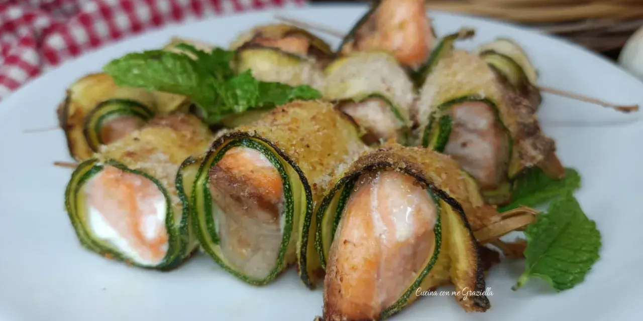 Deliziosi involtini di zucchine con salmone e formaggio, guarniti con menta fresca.