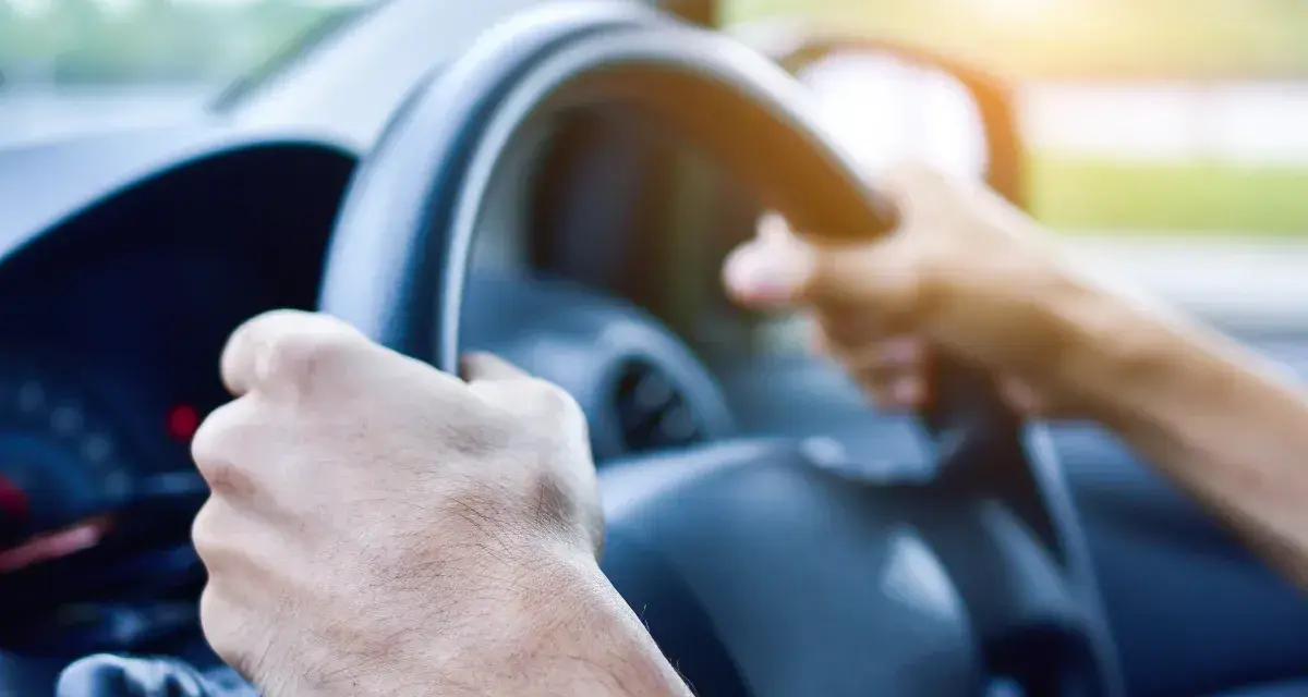 Dłoń trzyma smartfon z mapą i pinezką lokalizacji.