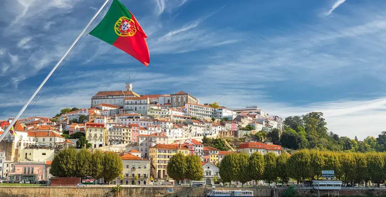 Wspaniała portugalia pogoda w grudniu. Flaga Portugalii powiewa nad malowniczym miastem na wzgórzu, z rzeką w tle.