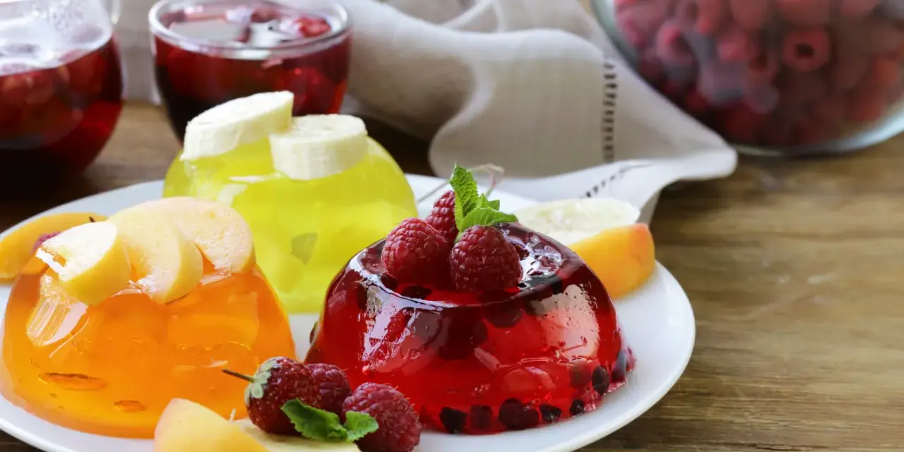 Tre colorate gelatine per dolci, guarnite con frutta fresca, invitano a un assaggio rinfrescante.
