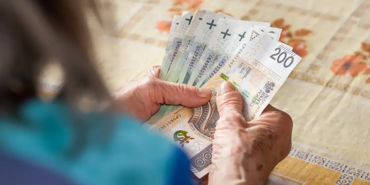 Dłonie starszej osoby liczą banknoty 200 zł. To może być ich 13 emerytura netto, która przynosi ulgę.