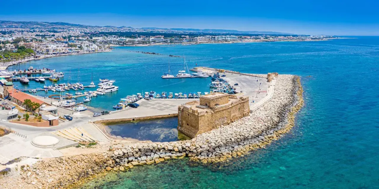 Pafos pogoda: Słoneczny dzień nad portem z zamkiem, jachtami i miastem w tle. Idealna pogoda na zwiedzanie Cypru.