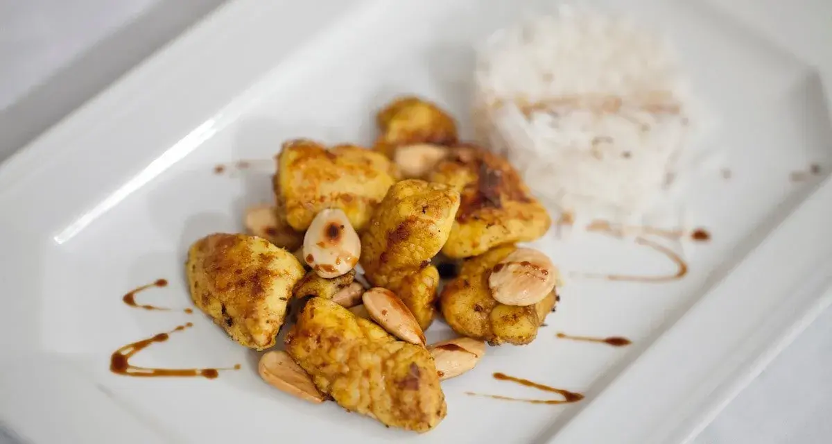 Piatto di cous cous con pollo al curry, mandorle e riso bianco.