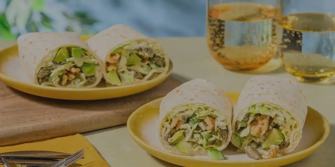 Leckeres Tortilla-Rezept mit Avocado und Garnelen, serviert auf gelben Tellern mit Gläsern mit Getränken.
