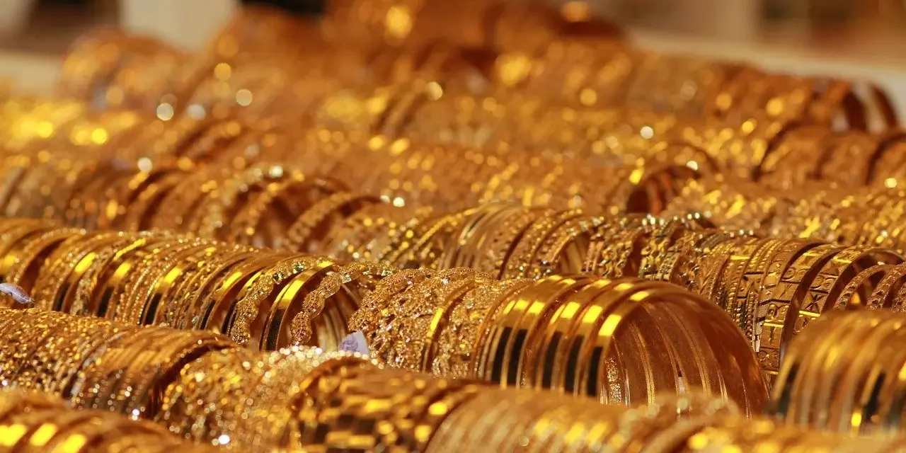 Una ricca collezione di bracciali d'oro, molti con il marchio 750, brillano sotto la luce, creando un'abbagliante esposizione di lusso.