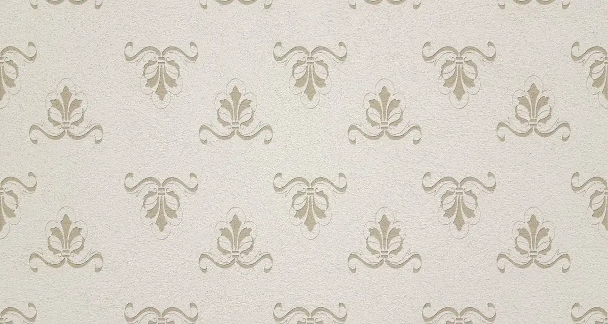Patrón repetitivo de ornamentos florales en relieve sobre un fondo texturizado. Este papel pintado transpirable aporta elegancia sutil.